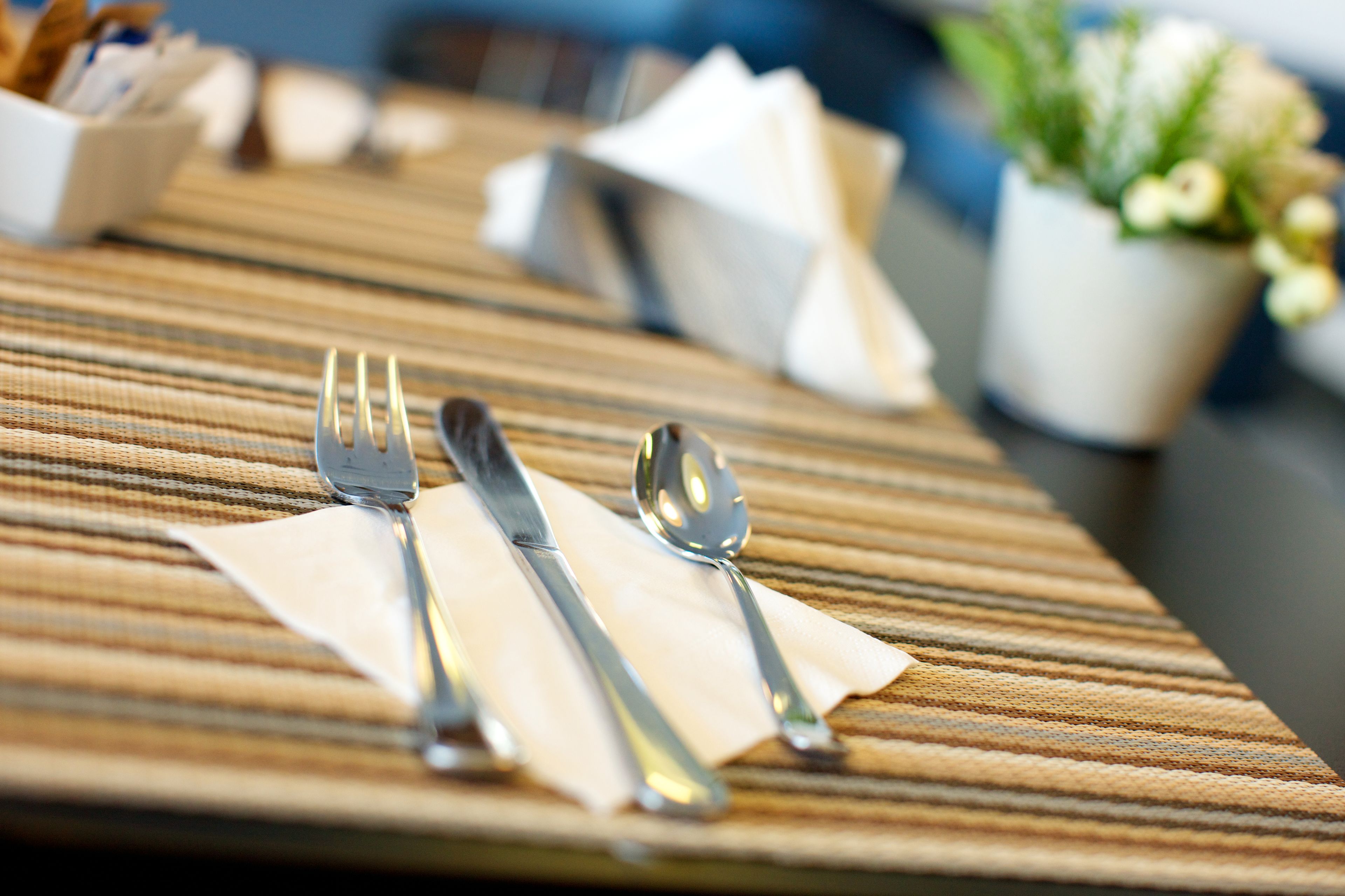 A neatly arranged dining table with cutlery and napkins.