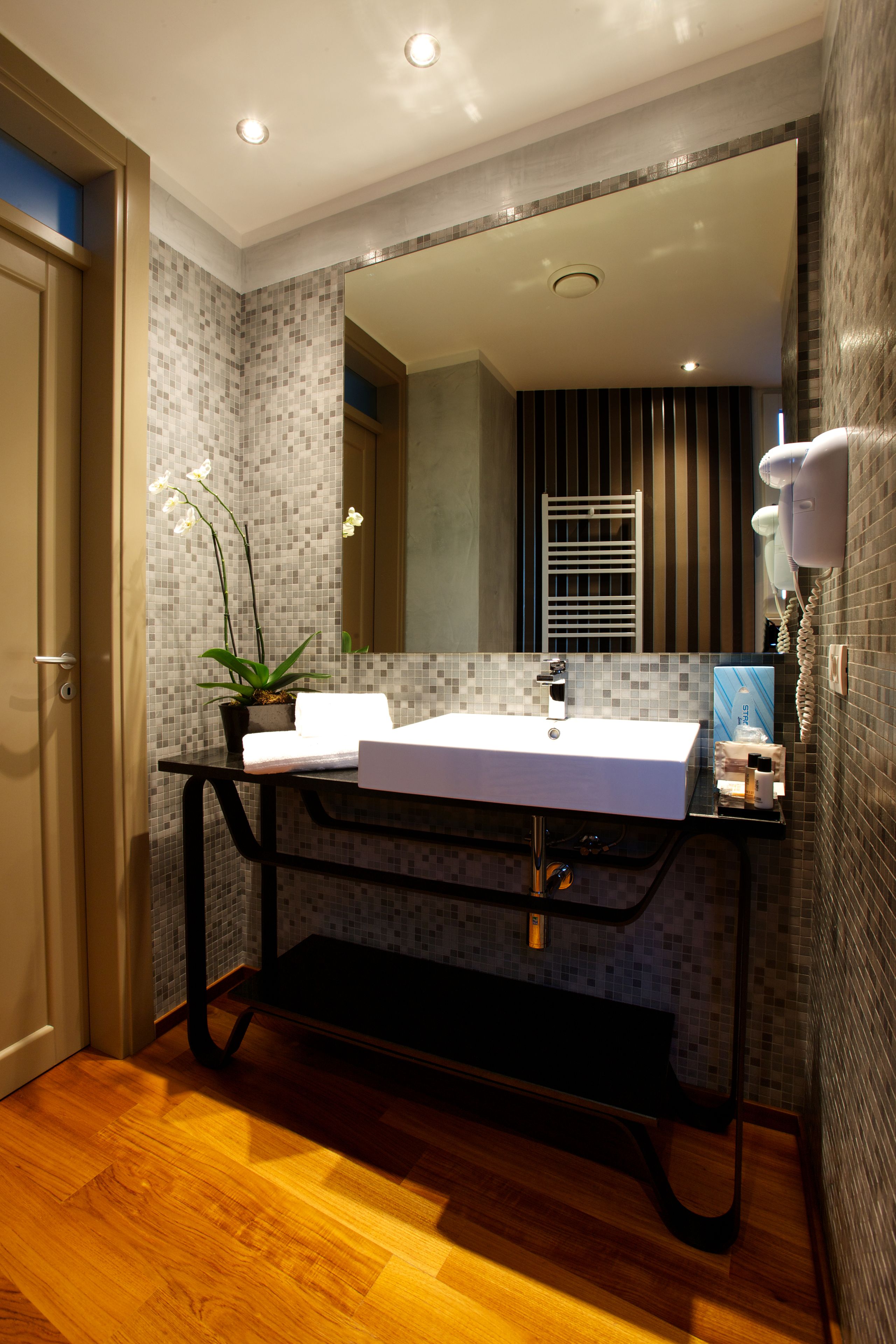 Een moderne badkamer met een wit wastafel, een potorkidee en een haardroger bevestigd aan de muur.