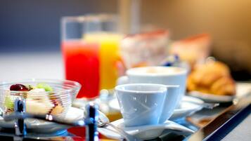 A breakfast tray with a glass of orange juice, a bowl of fruit, a croissant, and a cup.