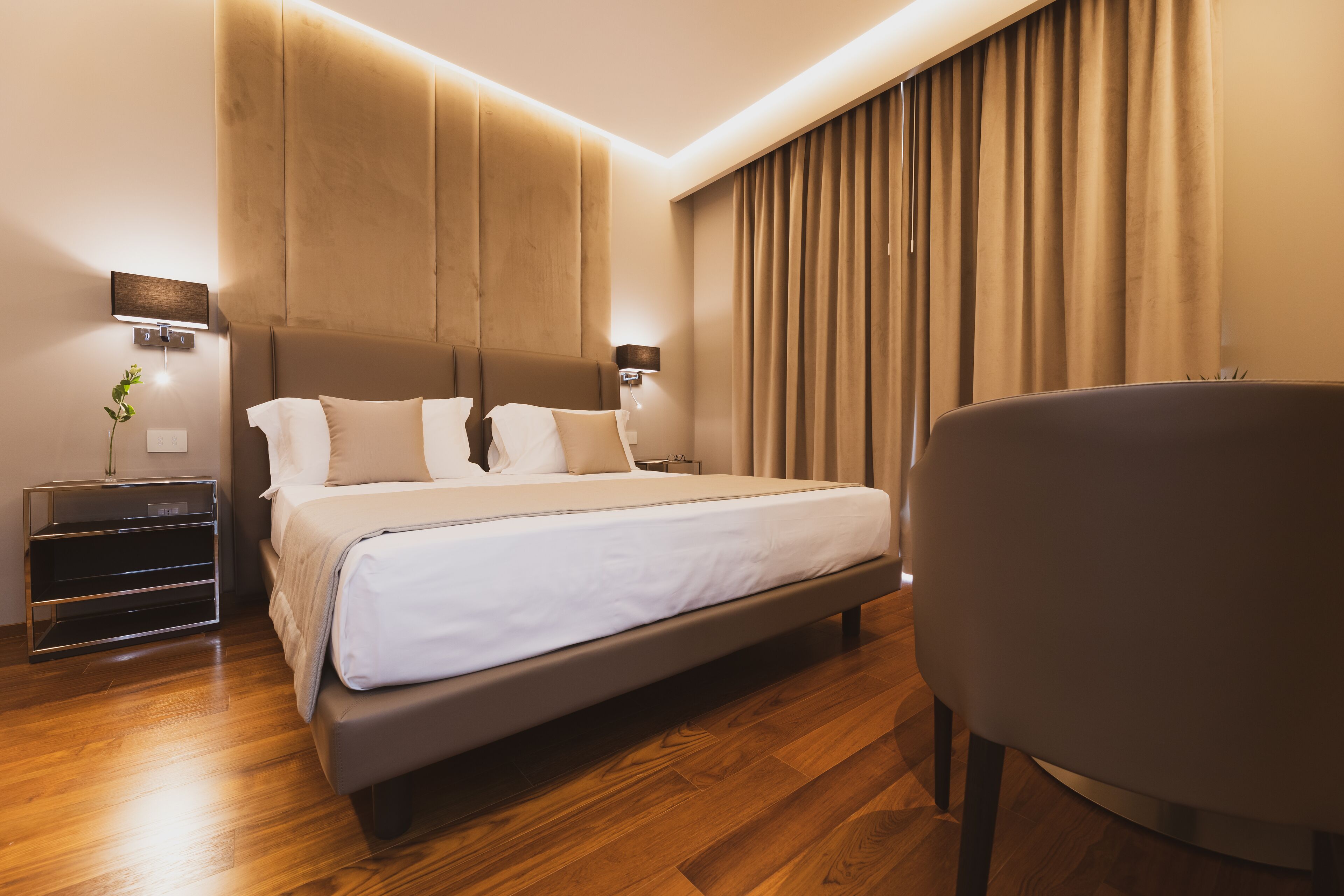 Una habitación de hotel moderna con una cama grande, mesitas de noche y una silla.