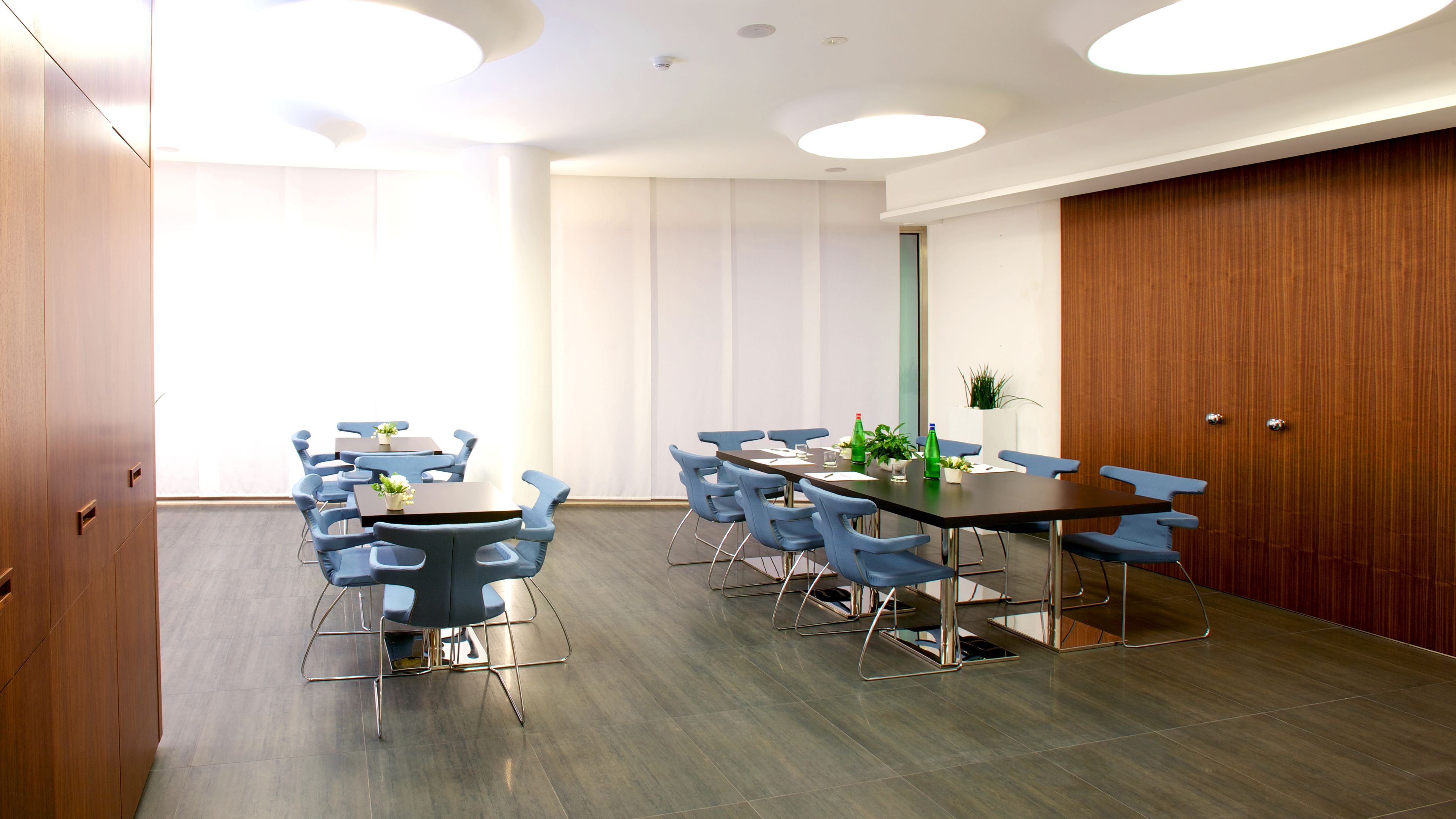 A conference room with a long table, blue chairs, and a wooden partition wall.