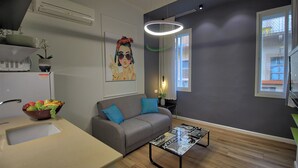 Ein modernes Wohnzimmer mit einem grauen Sofa, einem Couchtisch, einer Obstschale und einem Gemälde an der Wand.