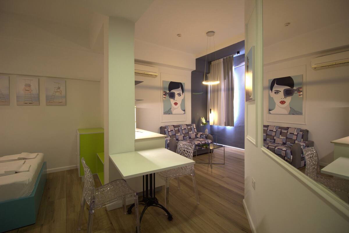 Una sala de estar moderna con un sofá, una mesa de comedor y una pequeña cocina.