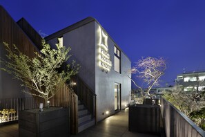A modern hostel with a sign reading "PEREC HOSTEL KYOTO" and a staircase leading to the entrance.