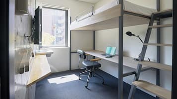 A bunk bed room with a desk, chair, and a window.