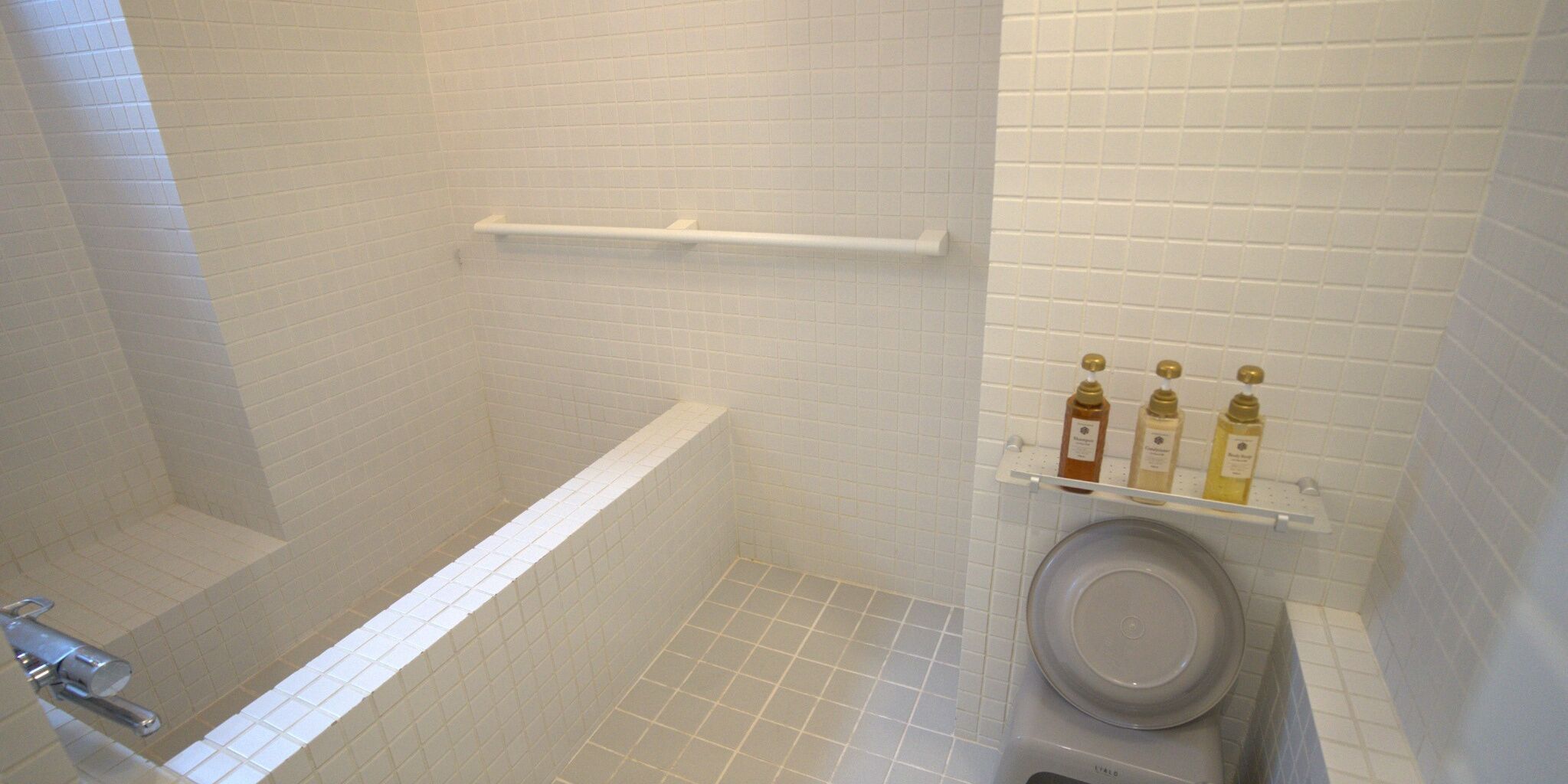 Un baño con bañera, inodoro y repisa con artículos de aseo.