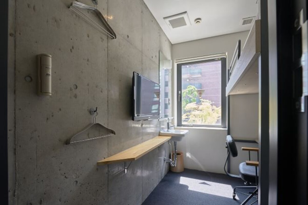A bathroom with a shower, a sink, a toilet, a towel rack, and a television mounted on the wall.