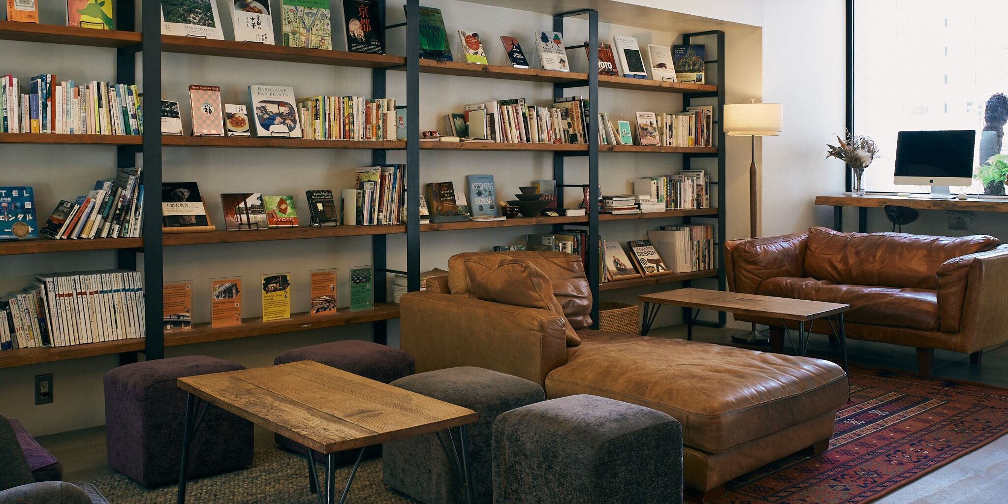 Una zona de lectura acollidora amb sofàs de pell, una taula baixa de fusta i una prestatgeria plena de llibres.