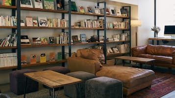 Una zona de lectura acollidora amb sofàs de pell, una taula baixa de fusta i una prestatgeria plena de llibres.