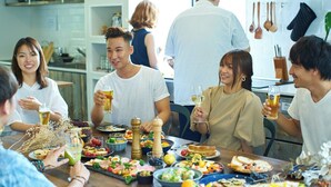 A group of people dining at a table with various dishes and drinks. - Piece Hostel Kyoto (Kyoto)