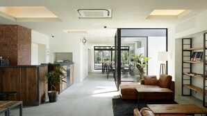 A modern interior with a kitchen area, a seating area with a sofa and coffee table, and a bookshelf. - Piece Hostel Kyoto (Kyoto)