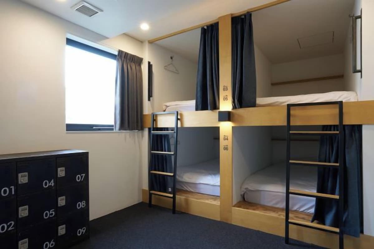 A bunk bed room with a window, a dresser, and a set of drawers.
