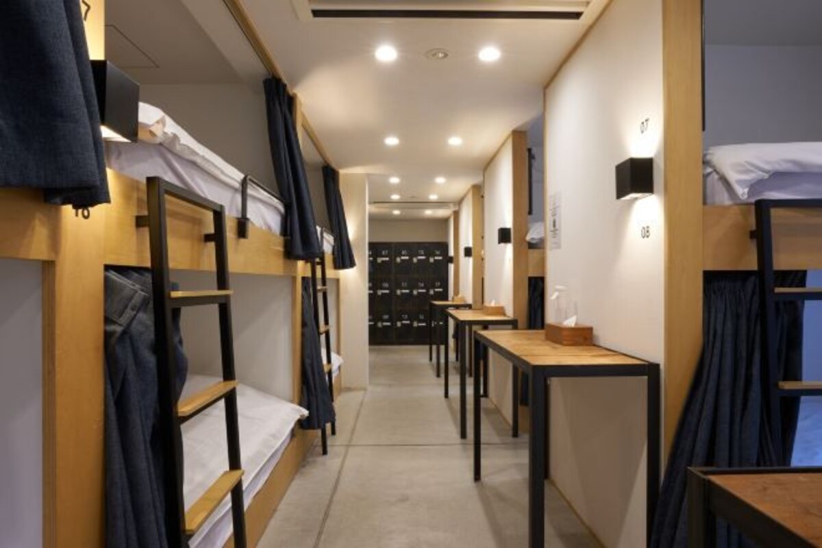 A corridor with bunk beds, tables, and storage units in a hotel room.