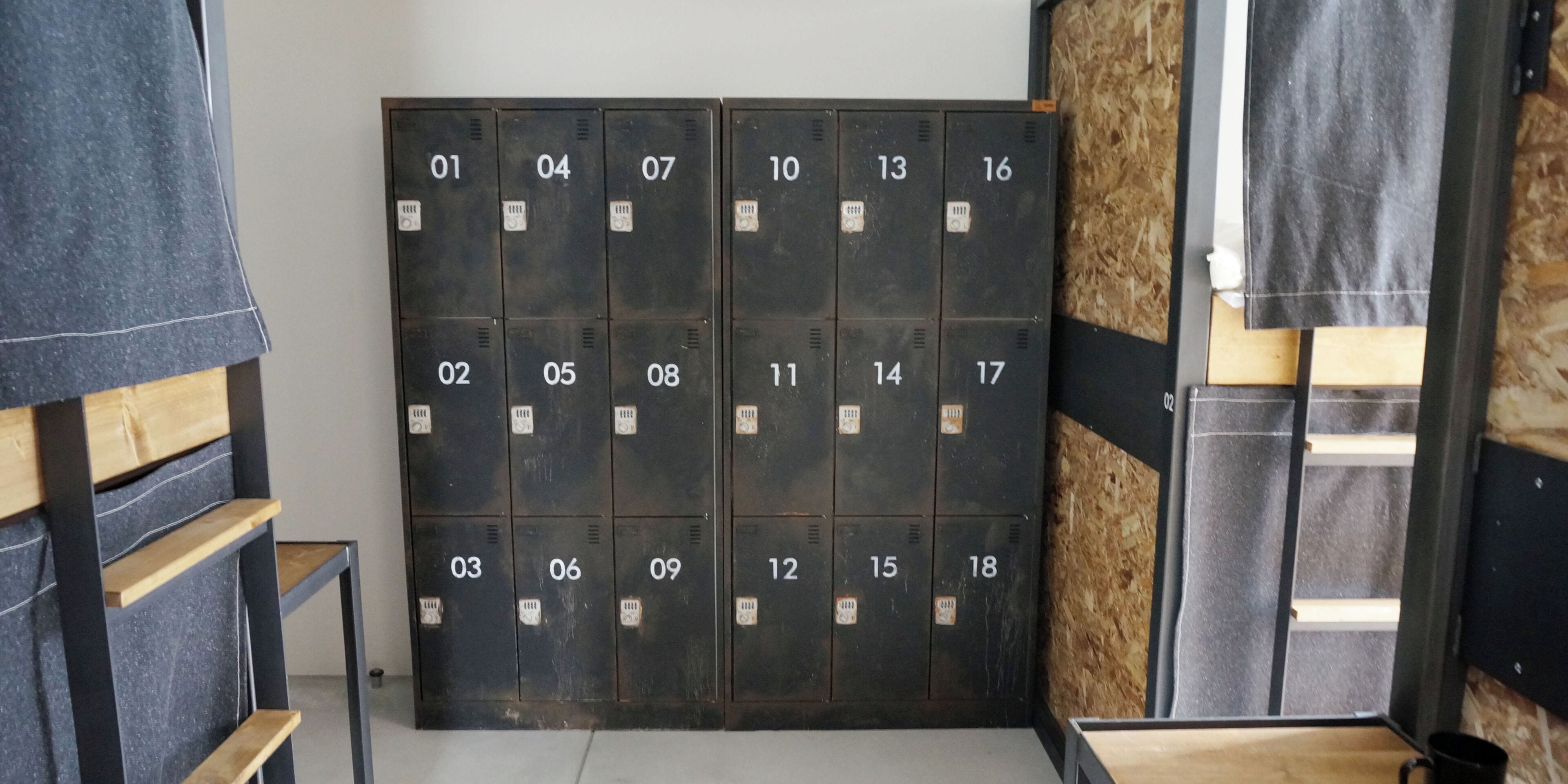 Une rangée de casiers numérotés dans une pièce où se trouvent un banc en bois et une structure métallique.