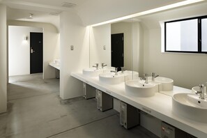 A modern bathroom with four sinks, a large mirror, and a black door. - Piece Hostel Kyoto (Kyoto)