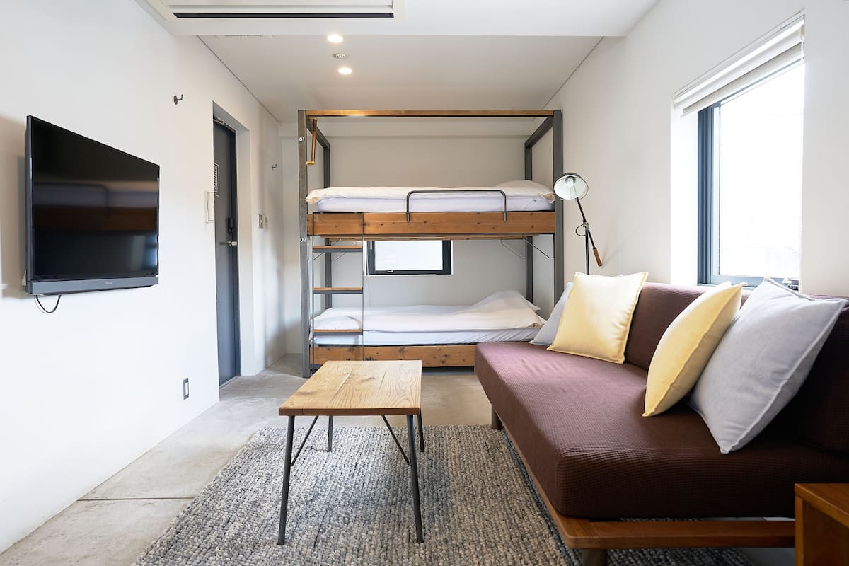 A compact room with bunk beds, a sofa, a TV, and a lamp.