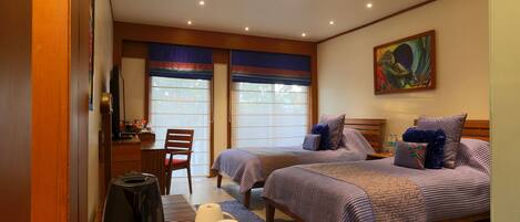 A hotel room with two beds, a desk, a chair, and a painting on the wall.