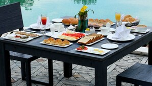 A breakfast table with various food items and drinks by a pool. - Brys Caves (Salt)