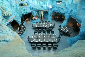 An ice-themed restaurant with tables set for dining, a central buffet, and a waiter standing. - Brys Caves (Salt)