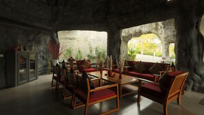 A modern interior with a stone wall, wooden furniture, and a view of greenery outside. - Brys Caves (Salt)
