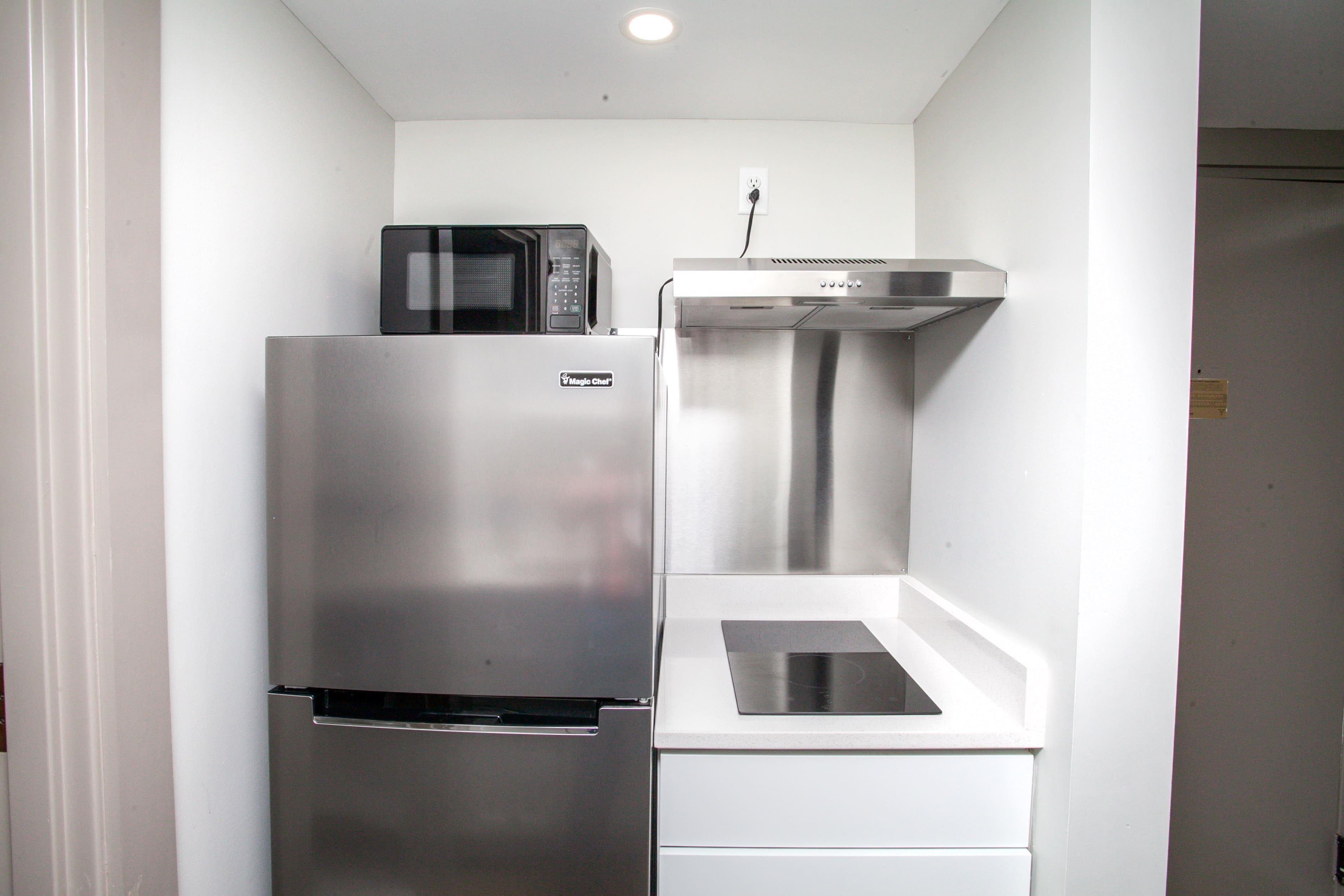 Una cocina compacta con un refrigerador de acero inoxidable, un microondas y un horno empotrado.