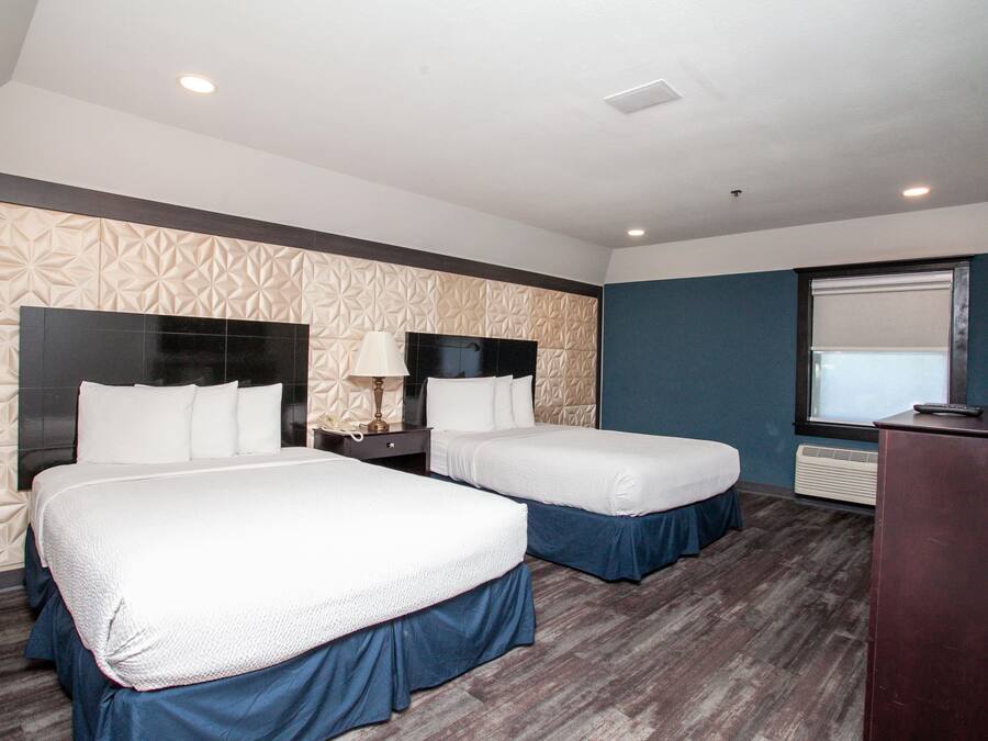 A hotel room with two beds, a desk, and a window.