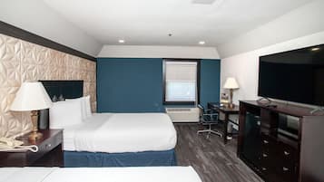 Ein Hotelzimmer mit einem Bett, einem Schreibtisch mit Lampe, einem Fernseher und einem Fenster.
