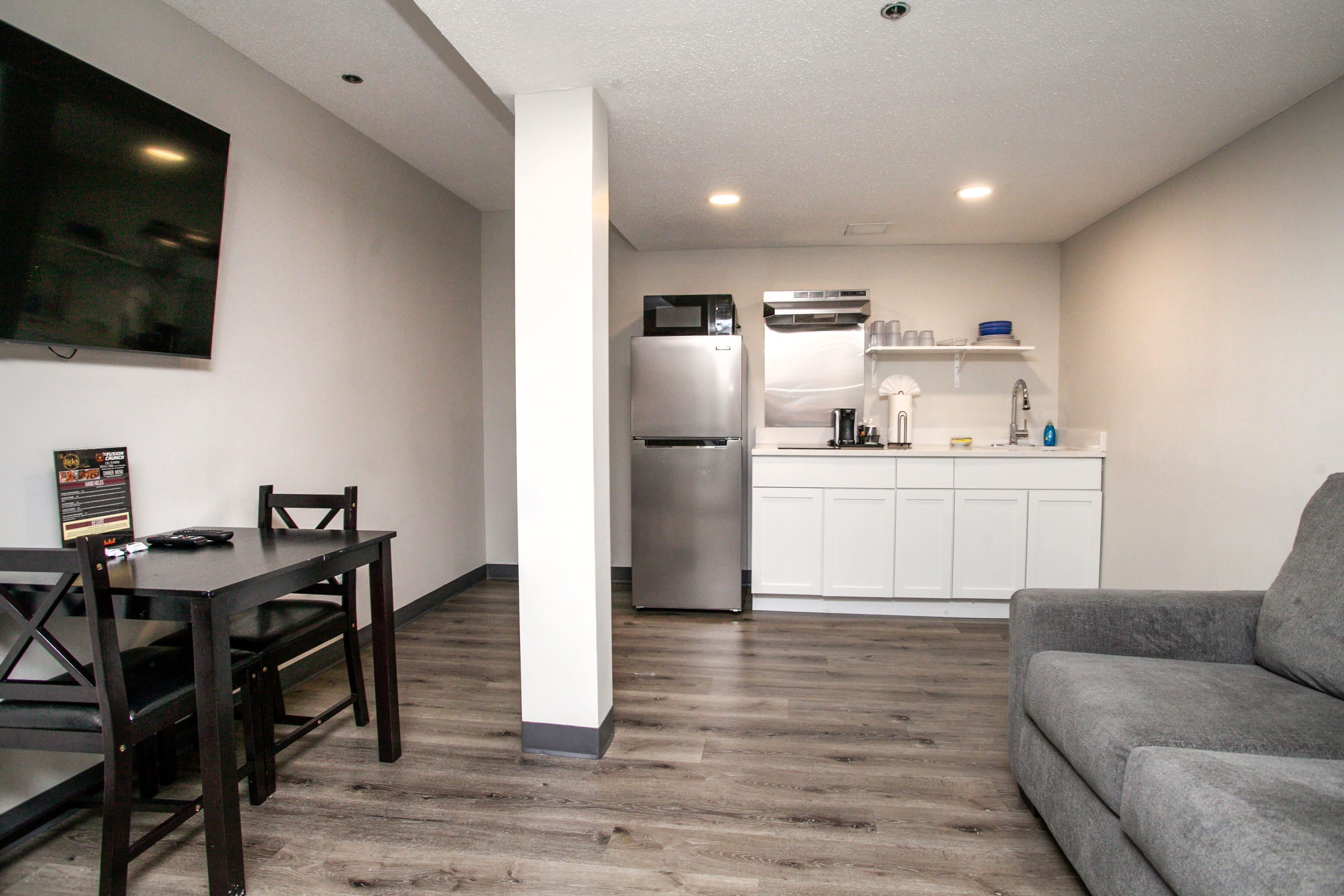 A compact living space with a dining area, kitchenette, and a gray sofa.