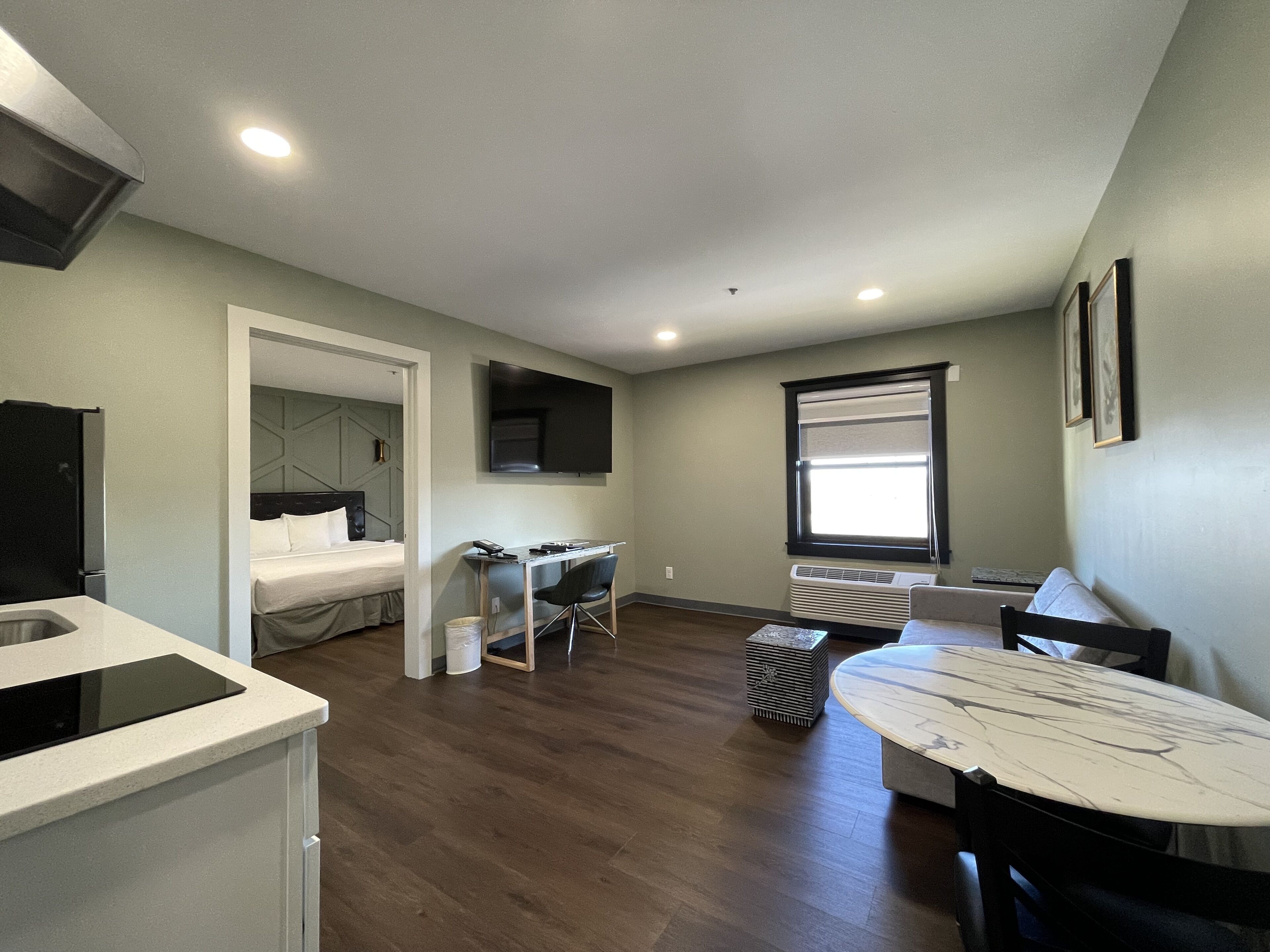 Una habitación pequeña con cama, escritorio, silla, mesa y televisor.