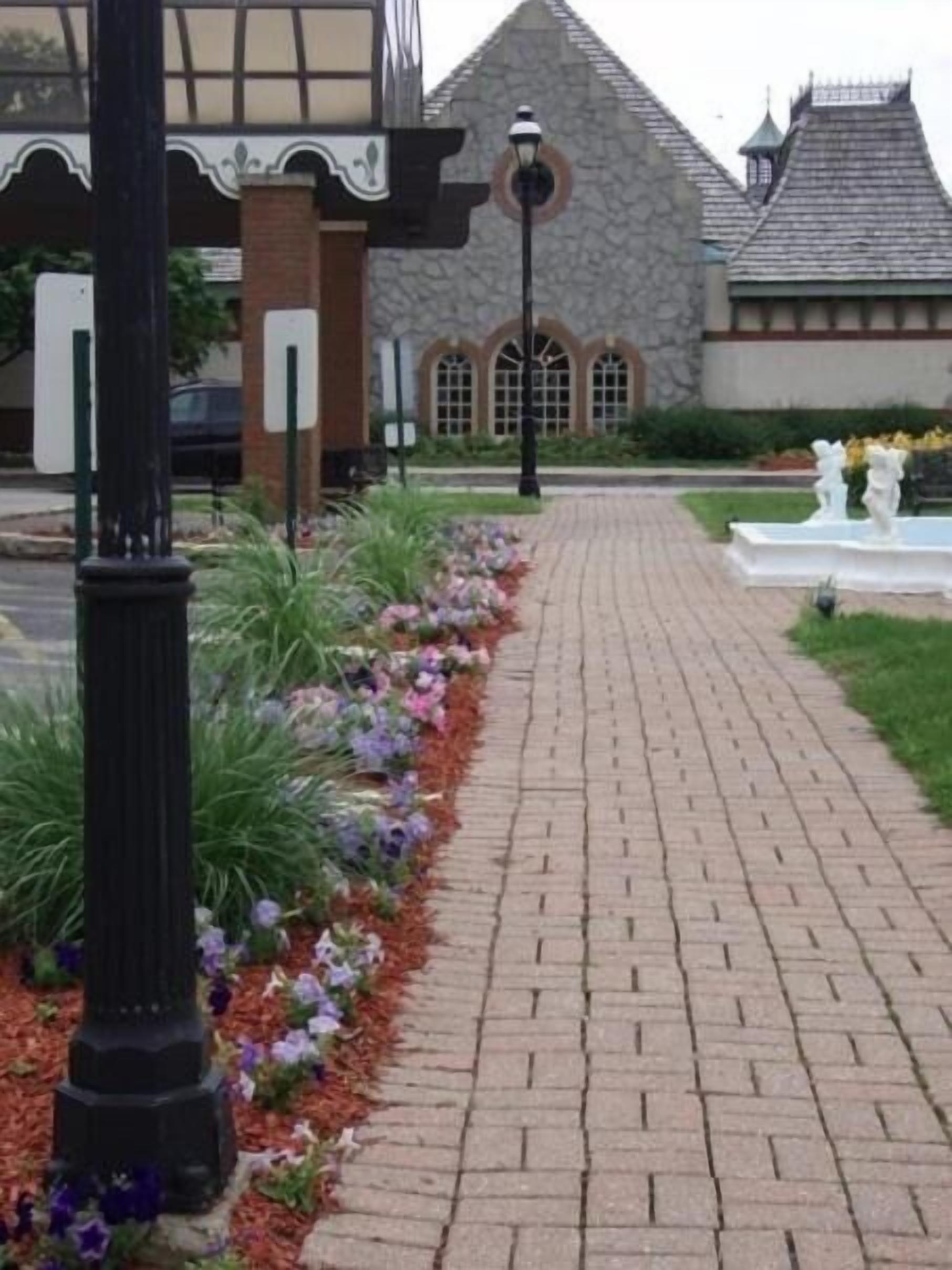 A paved pathway leading to a building with a stone facade and arched windows.