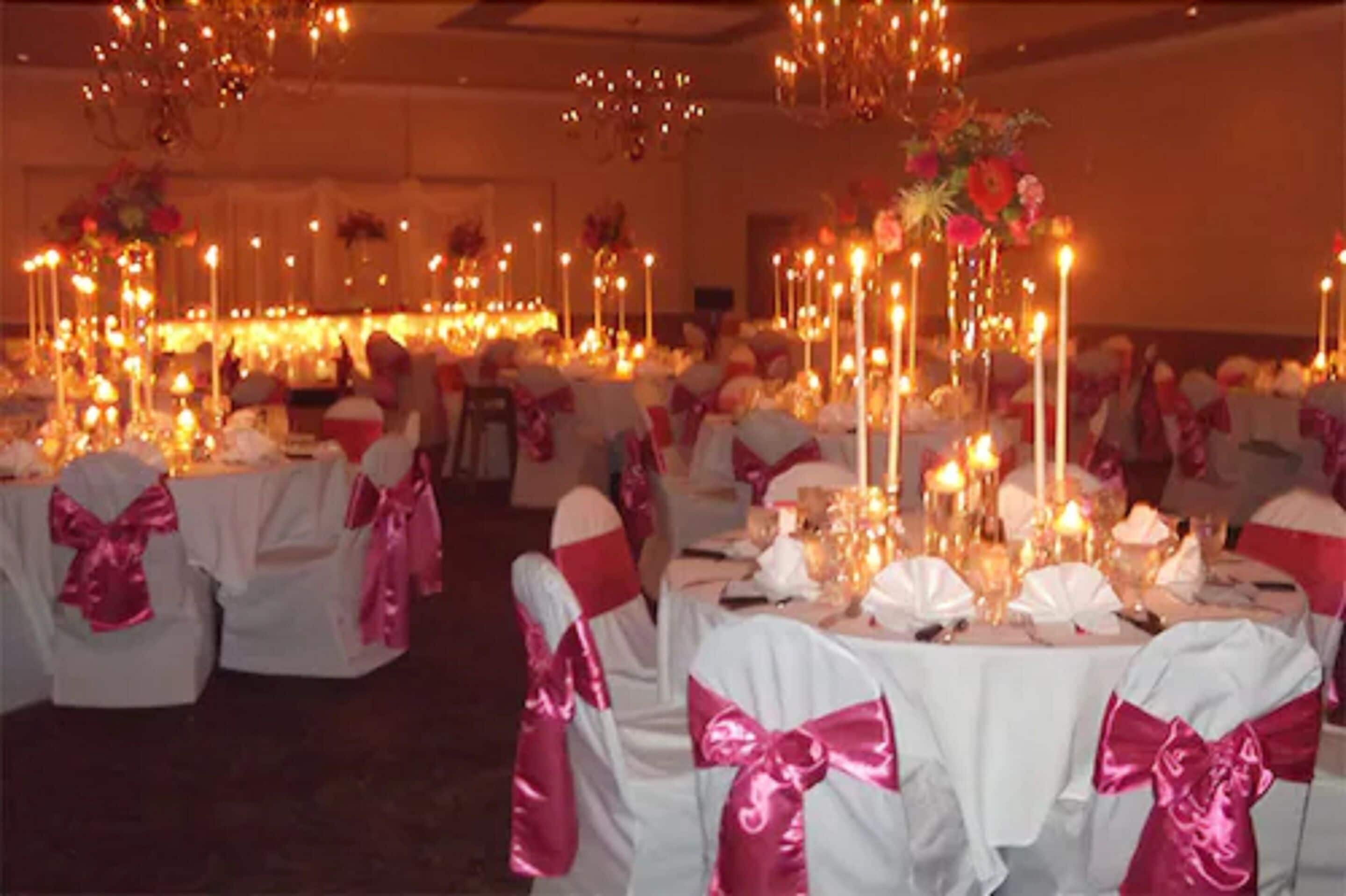A banquet hall with round tables, white tablecloths, and pink sashes.