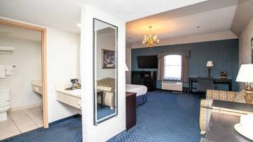 Une chambre d’hôtel comprenant un lit, un bureau, une chaise, une commode, un miroir, une télévision et une salle de bain.