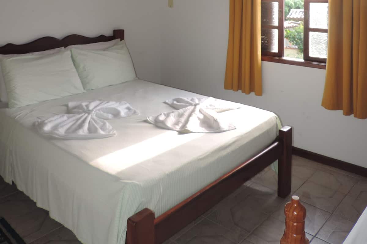 A neatly made bed with white linens, a wooden headboard, and a ceiling fan.