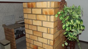 A kitchen with a brick wall, a sink, and a potted plant. - Flats Paguru (Búzios)
