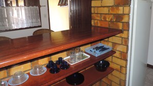 A kitchen with a wooden countertop, a brick wall, and a white refrigerator. - Flats Paguru (Búzios)