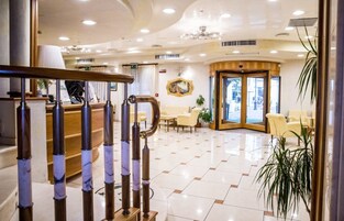 Un vestíbulo de hotel con mostrador de recepción, zona de estar y una escalera.