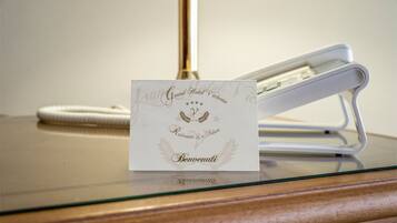 A hotel room with a glass table displaying a card that reads "Grand Hotel Victoria Restaurante La Feluca Benuenuti."