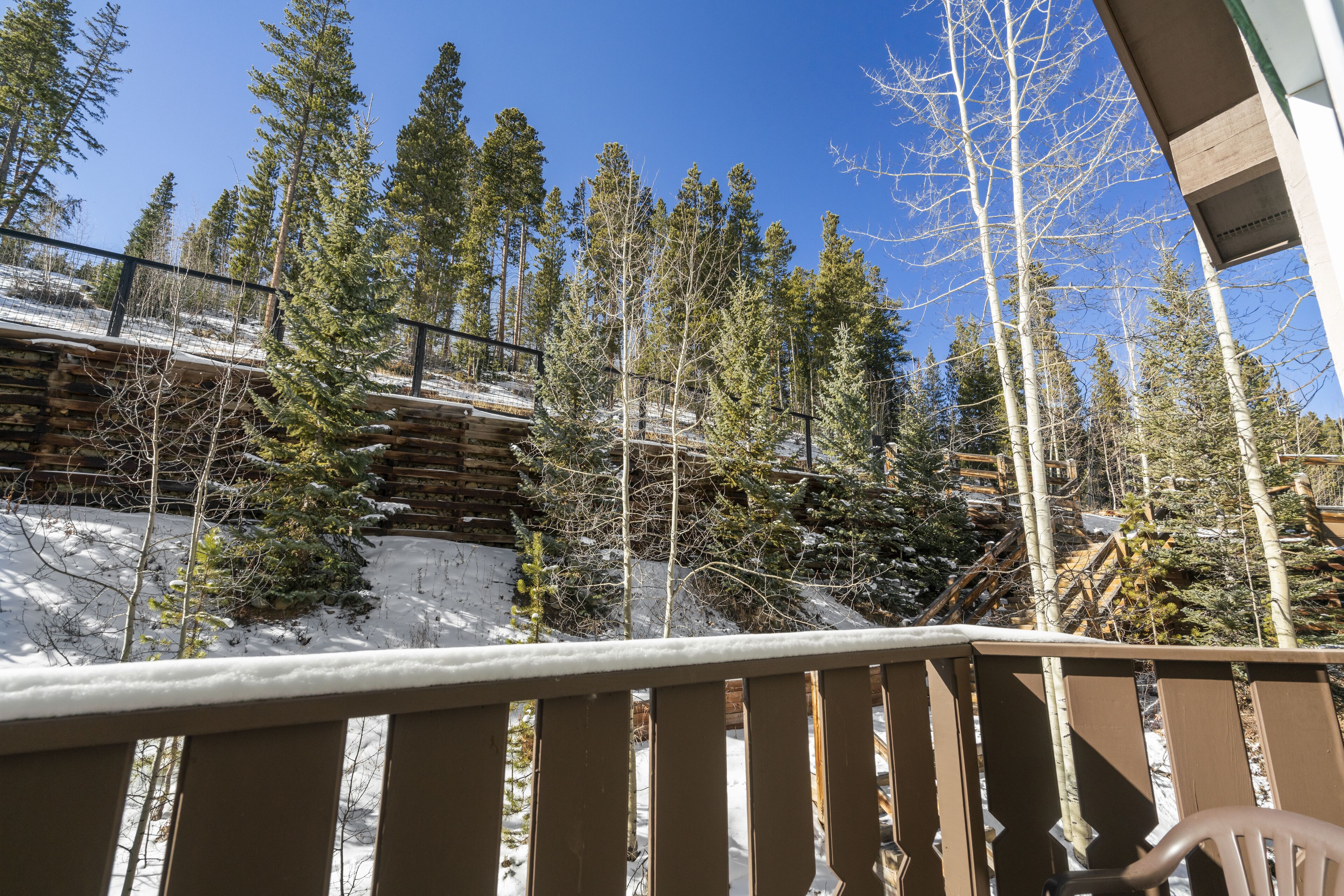 Un terrazzo in legno con vista su una foresta innevata e un edificio sullo sfondo.