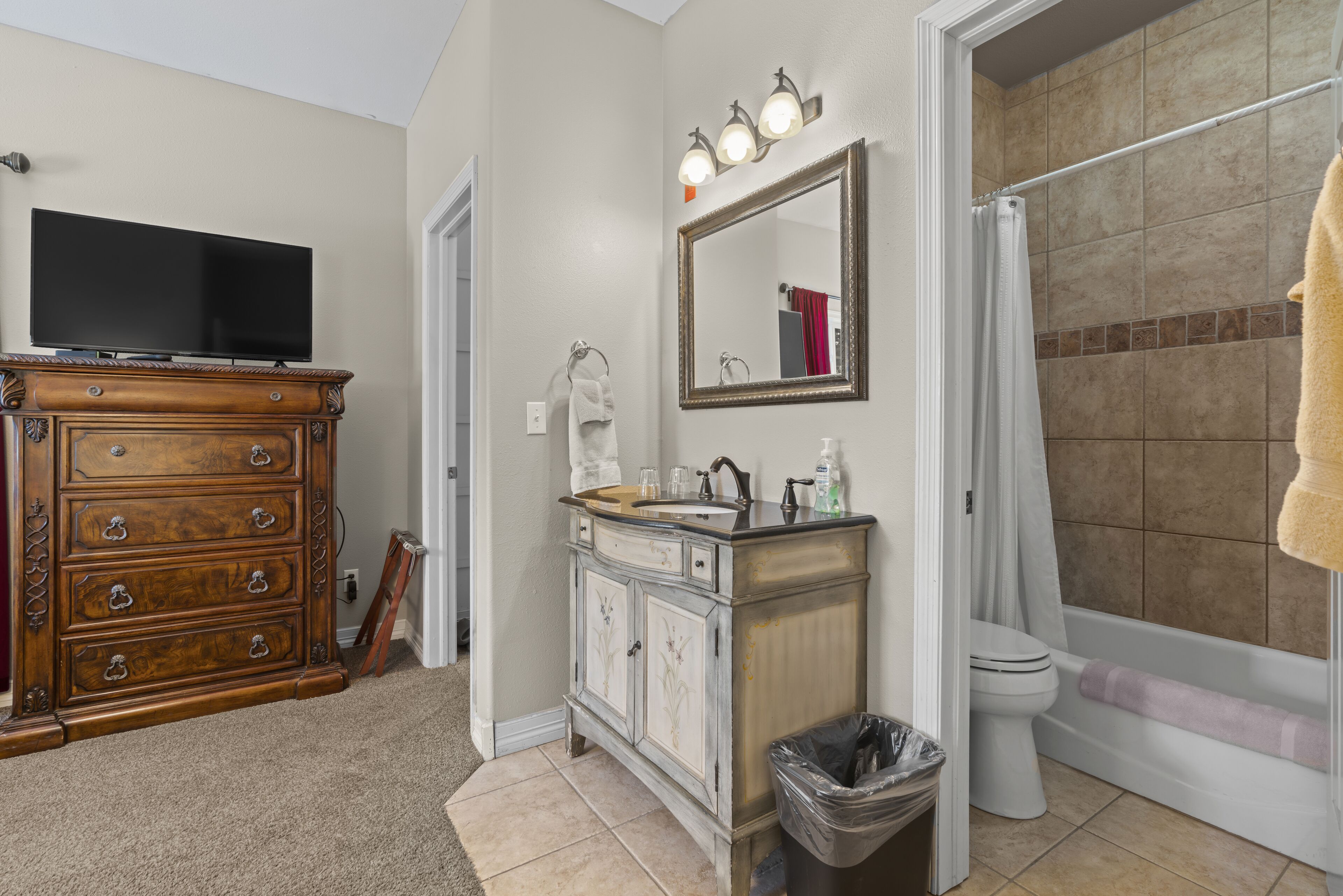 A bathroom with a vanity, sink, mirror, and toilet.