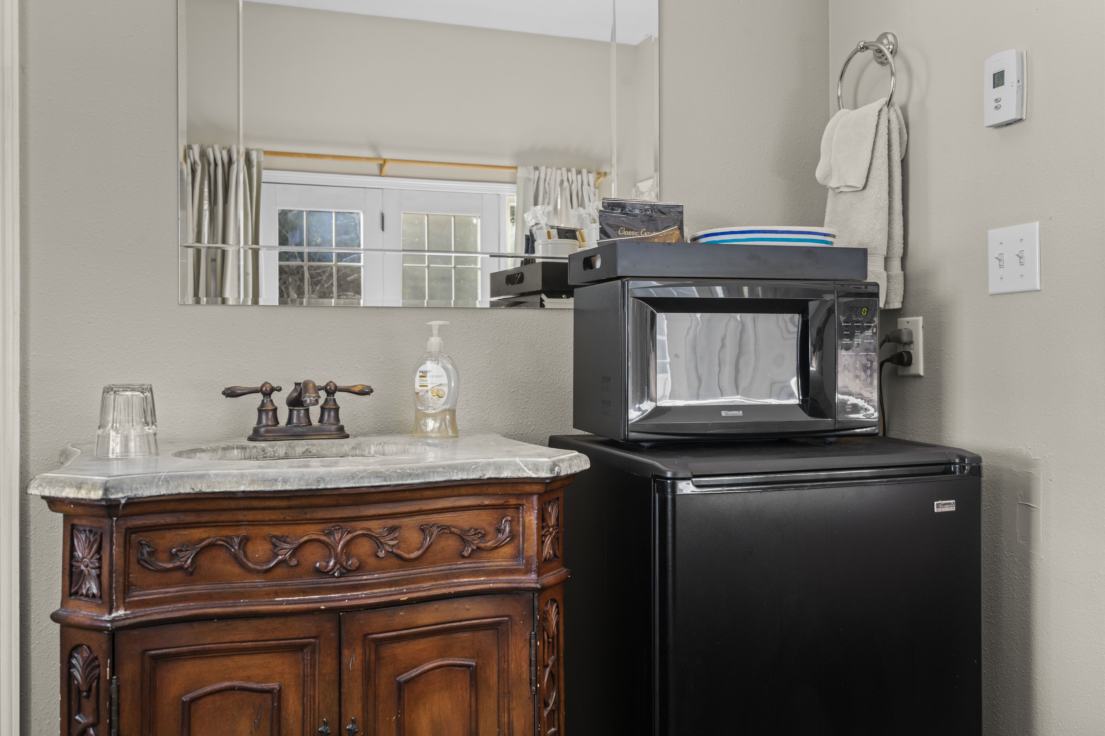 A kitchen with a wooden cabinet, a black refrigerator, a microwave, and a sink with a faucet.