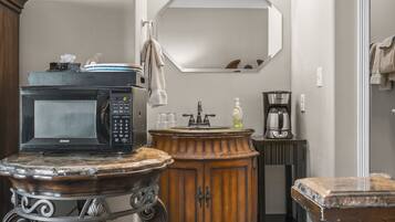 A bathroom with a sink, mirror, and a microwave on a small table.
