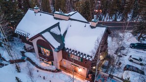 A large, multi-story house with a snow-covered roof and a visible swimming pool.