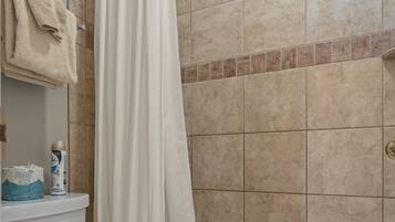 A bathroom with a toilet, a shower curtain, and a bathtub.