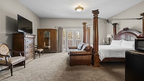 A bedroom with a four-poster bed, a dresser, a television, a desk, and a chair.