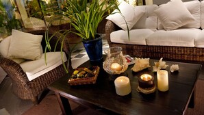 A cozy seating area with wicker furniture, a potted plant, candles, and decorative items on a dark wooden table. - Hotel Atlantic Riviera (Misano Adriatico)