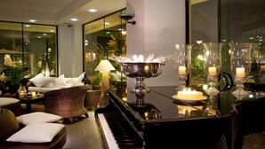 A piano, a candle-lit table, and wicker furniture in a well-lit indoor space. - Hotel Atlantic Riviera (Misano Adriatico)