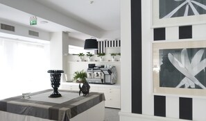 A modern kitchen with white cabinetry, a coffee machine, and potted plants. - Hotel Atlantic Riviera (Misano Adriatico)
