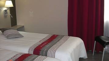 A hotel room with two beds, a nightstand, a lamp, a chair, and a wall art piece.