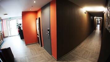 Een hal met een modern design, met een combinatie van oranje en donkere wanden en een betegelde vloer.