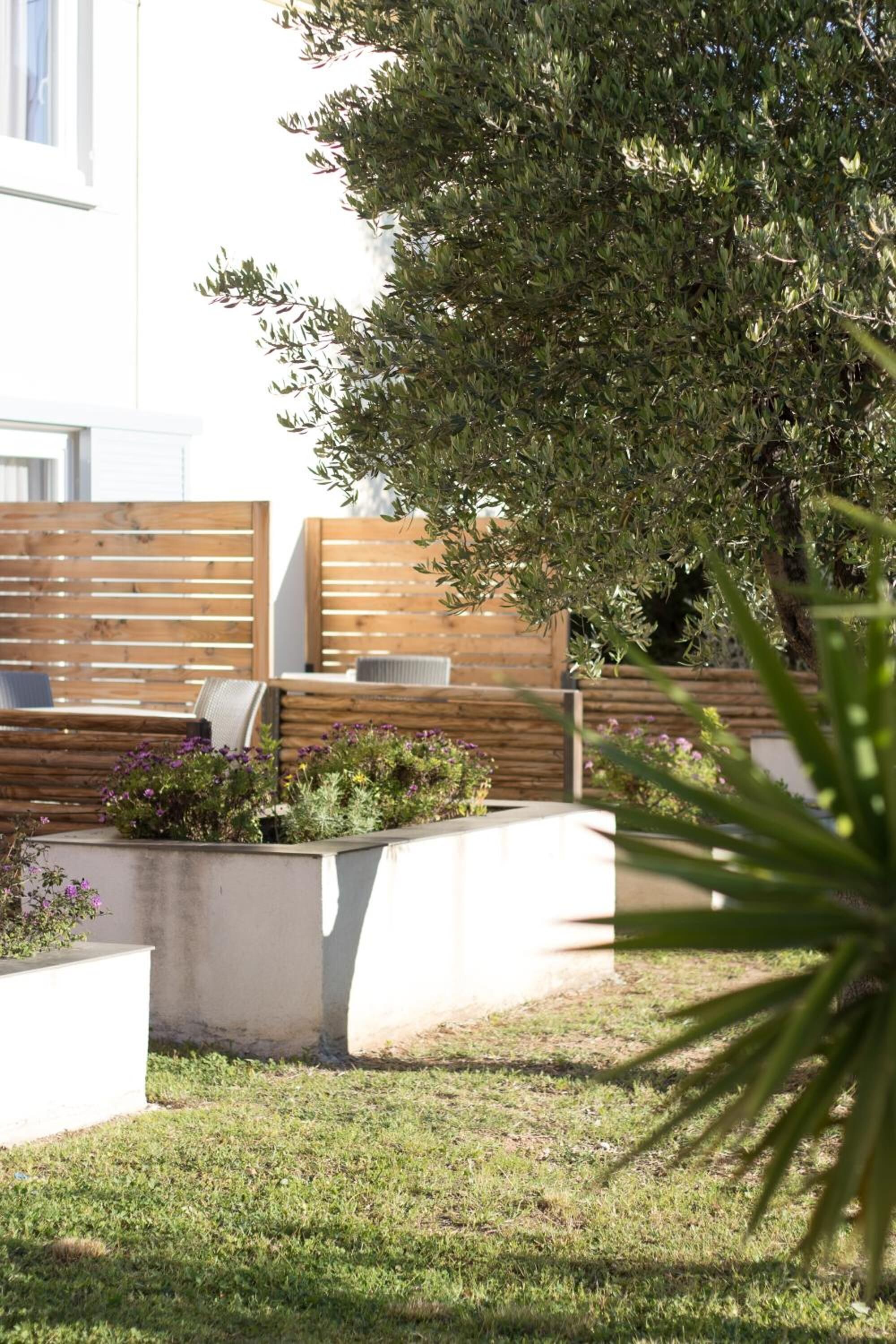 Een modern buitenzitgedeelte met houten banken en plantenbakken.